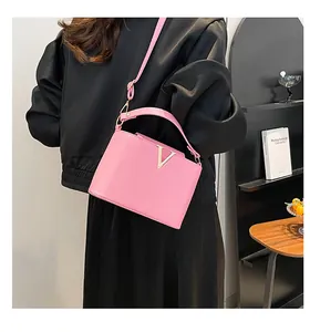 Détail d'un sac à main rose en cuir grainé avec logo V doré et bandoulière réglable