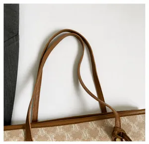 Detalle de asas de cuero con remaches metálicos en un bolso tote con estampado