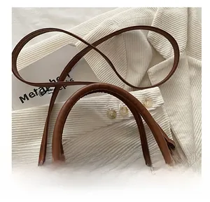 Détail du sac en cuir grainé avec poignée ronde marron et finitions métalliques dorées