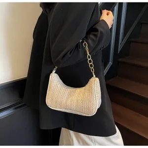 Detail showing the straw weave texture and gold chunky chain strap of this crescent hobo bag