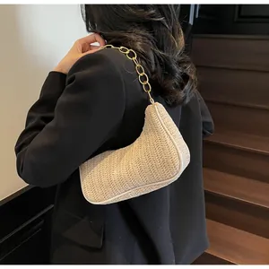 Detail of woven crescent shoulder bag with golden chain strap on a chic black blazer