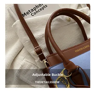 Détail de la boucle réglable et de la bandoulière en cuir brun sur le sac bleu