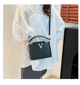 Détail du sac seau en cuir noir avec un logo en V doré métallique sur le devant de l'article