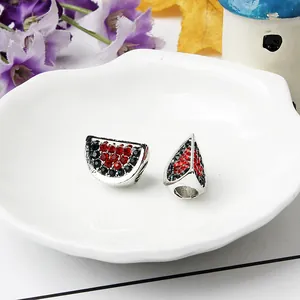 Dettaglio macro di ciondoli anguria con strass rossi e verdi per bracciali fai-da-te