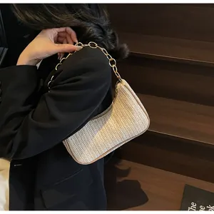 Detail view of woven beige crescent bag with gold chain strap on model's shoulder