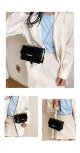 Detail of glossy black patent leather shoulder bag with golden chain and metal buckle