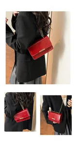 Macro view of red patent leather handbag featuring glossy finish and gold metal bar detail