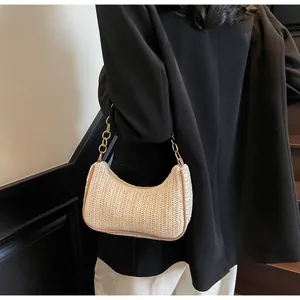 Detail showing wavy woven texture of beige straw shoulder bag with elegant gold chain