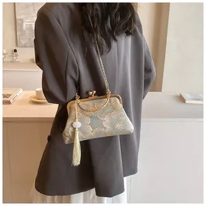 Detail der hellblauen Qipao-Tasche mit goldener Blumenstickerei und Quaste