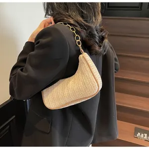 Detail of beige woven hobo bag featuring a chunky gold chain strap worn by a model