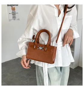 Detail of brown crocodile embossed leather handbag with metal buckle and shoulder strap