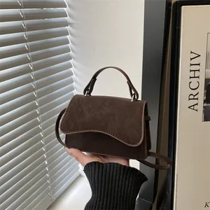 Chic dark brown suede crossbody bag with wave flap and silver metallic details