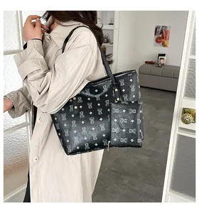 Detail of printed black tote bag set and mini clutch on model with beige coat