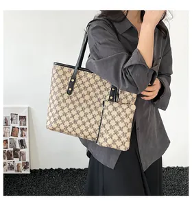 Detail of trendy monogram tote bag set with matching pouch and black leather straps