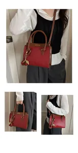 Detail of red and brown contrast leather handbag with cherry pendant and logo