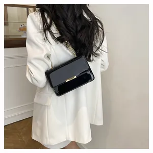 Detailed view of glossy black patent leather bag with a stylish gold chain strap