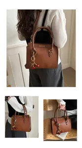 Detail of brown litchi pattern leather tote bag featuring a cute cherry metal charm