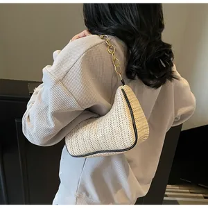 Detail of cream straw shoulder bag with V-weave texture and chunky gold chain strap