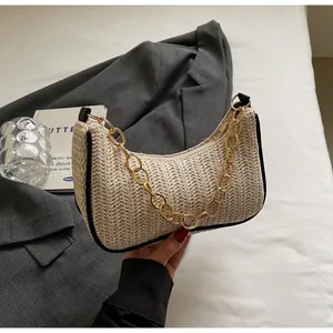 Detailed close-up of straw crescent bag featuring thick gold chain and black edge trim