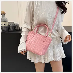 Detail of pink woven PU leather shoulder bag with gold metal buckles and crossbody strap