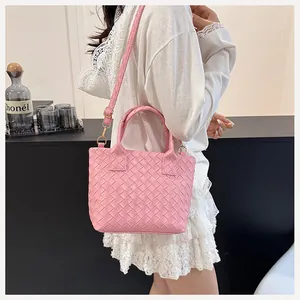 Detail of pink woven texture crossbody bag with gold hardware and adjustable strap
