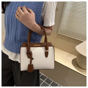 Close-up of contrast stitching and gold lettering on white lychee leather handbag