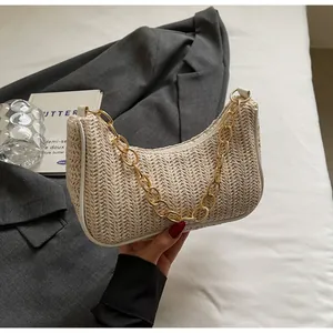 Detail of straw woven crescent bag with coarse gold chain and herringbone texture