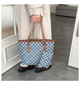 Close-up of the blue and white monogram tote bag with brown leather trim and hanging pouch