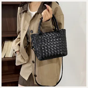 Close-up of black woven tote bag featuring vegan leather finish and adjustable strap