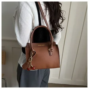 Vue détaillée du sac à main marron en cuir grainé avec breloque cerise et lettrage doré