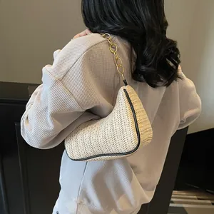Chic cream woven crescent bag with thick gold chain strap and black trim on model