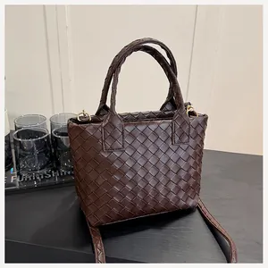 Detail of the dark brown woven texture and polished gold hardware on this tote bag