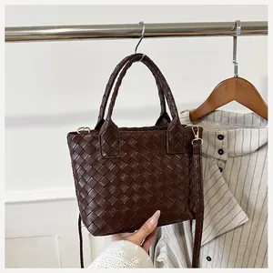 Detailed close-up of dark brown woven leather Boston bag with gold-tone hardware detail