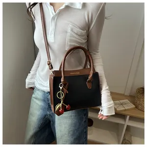 Détail du sac à main bicolore en similicuir avec pendentif cerise et dorure