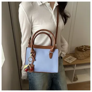 Détail du sac cabas bleu clair avec rabat marron et pendentif cerise