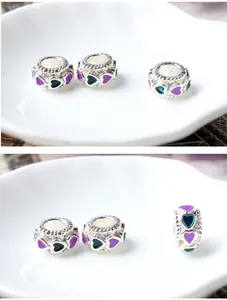 Macro detail of silver charm bead with purple and teal enamel heart patterns for DIY jewelry