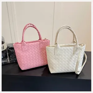 Detailed view of woven pink and off-white handbags with intricate braided texture