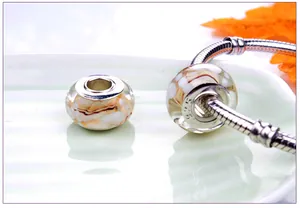 Macro detail of amber glass bead with S925 silver core on a snake chain bracelet