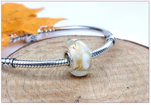 Close-up of glass bead with white paw print on silver snake chain bracelet