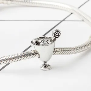 Dettaglio di un ciondolo a forma di bicchiere da cocktail vintage su bracciale a maglia snake