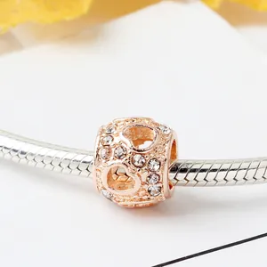 Roségouden holle hart-charm met zirkonia kralen aan een zilveren slangenschakel armband