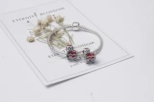 Dettaglio dei ciondoli a leone smaltati rossi su bracciale a maglia snake
