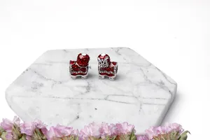 Dettaglio di ciondoli leone danzante in smalto rosso con strass su base di marmo bianco