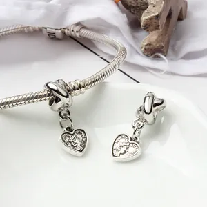 Macro view of silver heart pendant with Queen portrait on a snake bone chain bracelet