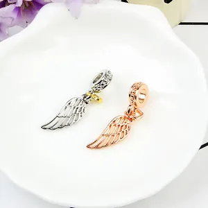 Detail of silver and rose gold hollow angel wing pendants with beaded charm rings