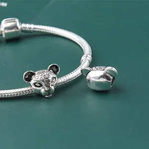 Macro shot of silver leopard head charm with detailed spots on snake bone chain bracelet