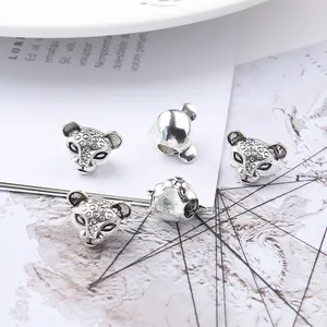 Macro shot of silver-colored leopard head charm beads with detailed engraving for DIY jewelry