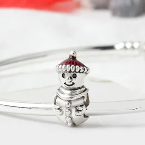 Makroaufnahme eines Schneemann-Anhängers aus Silber mit rotem Emaille-Hut auf Armband