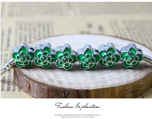 Détail de perles de fleurs en émail vert sur un bracelet chaîne serpent