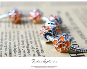 Détail macro du bracelet chaîne serpent en argent avec cinq fleurs en émail orange
